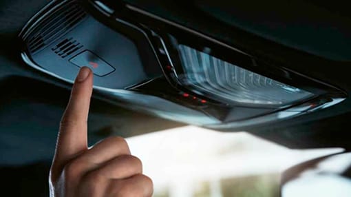 Image of a person's hand pressing the button for BMW Assist
