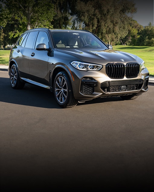 A Certified Pre-Owned BMW X5 and 5 Series sedan drive along side each other on a road