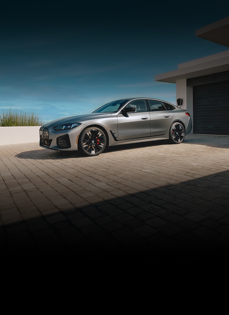The BMW i4 M50 on a brick paved driveway of a modern home