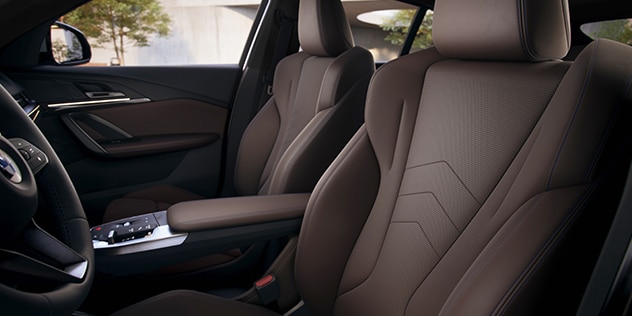 Interior shot of BMW front row, showing seats, arm rest, and wheel