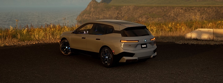 Rear angled view of a 2025 BMW iX parked overlooking the ocean.