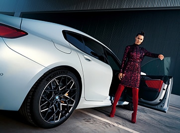 A woman opens the passenger side door of the 2025 BMW M8 Competition Gran Coupe
