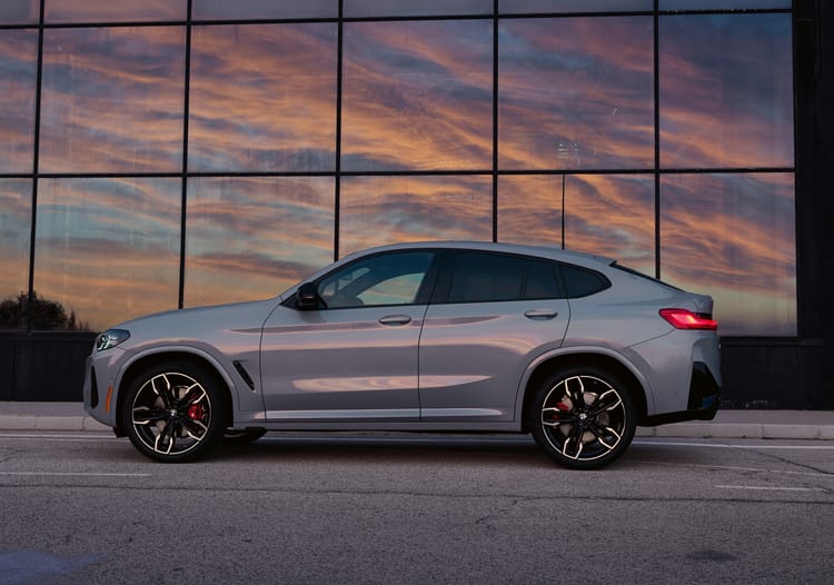 2025 BMW X4 parked in front of a building with the sunset in the background