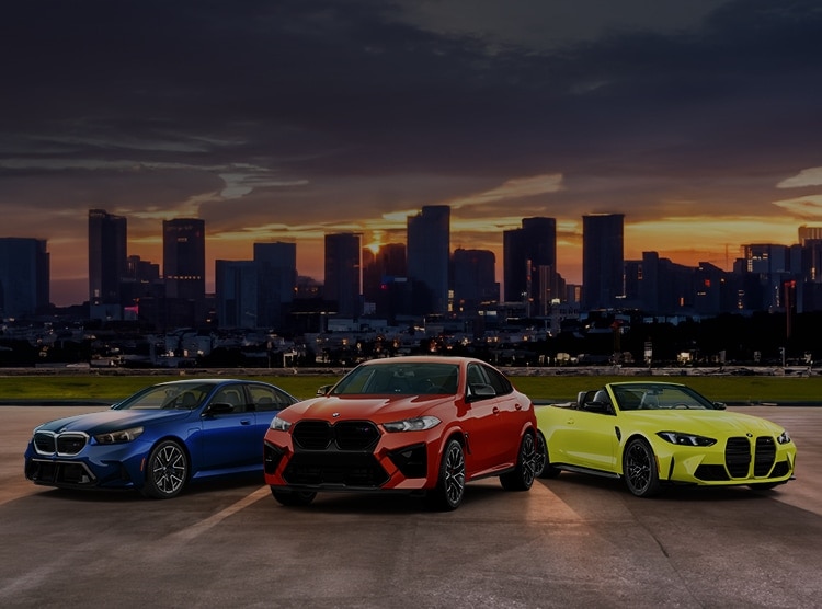 The BMW M5, X5 M, and M4 Competition Convertible parked in front of a city backdrop 