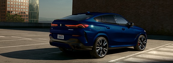 3/4 rear view of a 2026 BMW X6 Coupe SUV parked in an urban setting