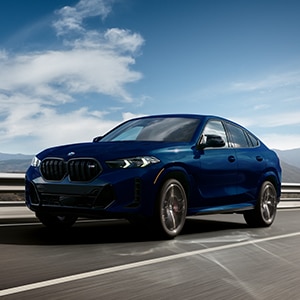 3/4 shot of the 2024 BMW X6 in motion on a rural highway