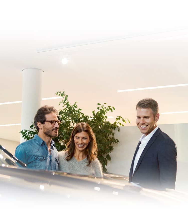 Shoppers at a BMW Center look over a Sports Activity Vehicle with their BMW dealer.