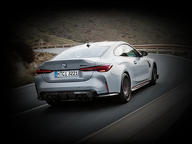 Rear action shot of the Limited Edition BMW M4 CSL, driving on an open curvy road – showcasing lightweight carbon fiber hood, rear diffuser and trunk with integrated ducktail