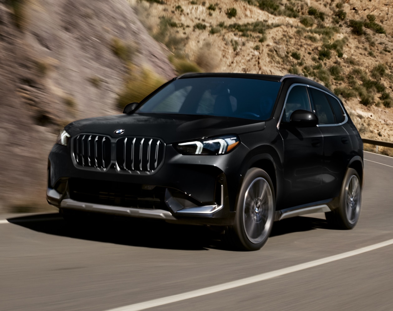Dynamic side profile shot of the BMW X1 navigating mountainous terrain