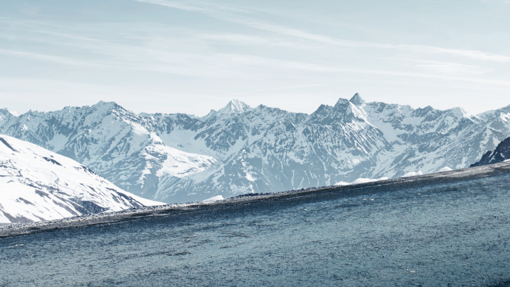 A wintry scene with snow-capped mountains and a challenging road