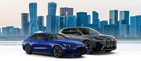 Two BMW Electrified-Performance M vehicles parked parallel to eachother in front of a city skyline